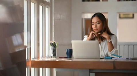 A worker is seated at a desk, looking at a computer.